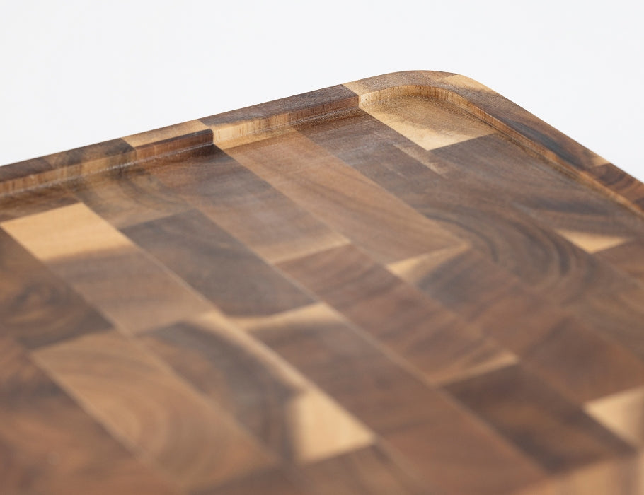 Close-up van de hoek van een Namture snijplank van acaciahout met een ingefreesde sapgeul en afgeronde randen.