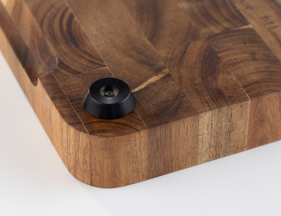 Close-up van de onderkant van een Namture snijplank van acaciahout met een zwart antislip voetje en afgeronde hoeken.
