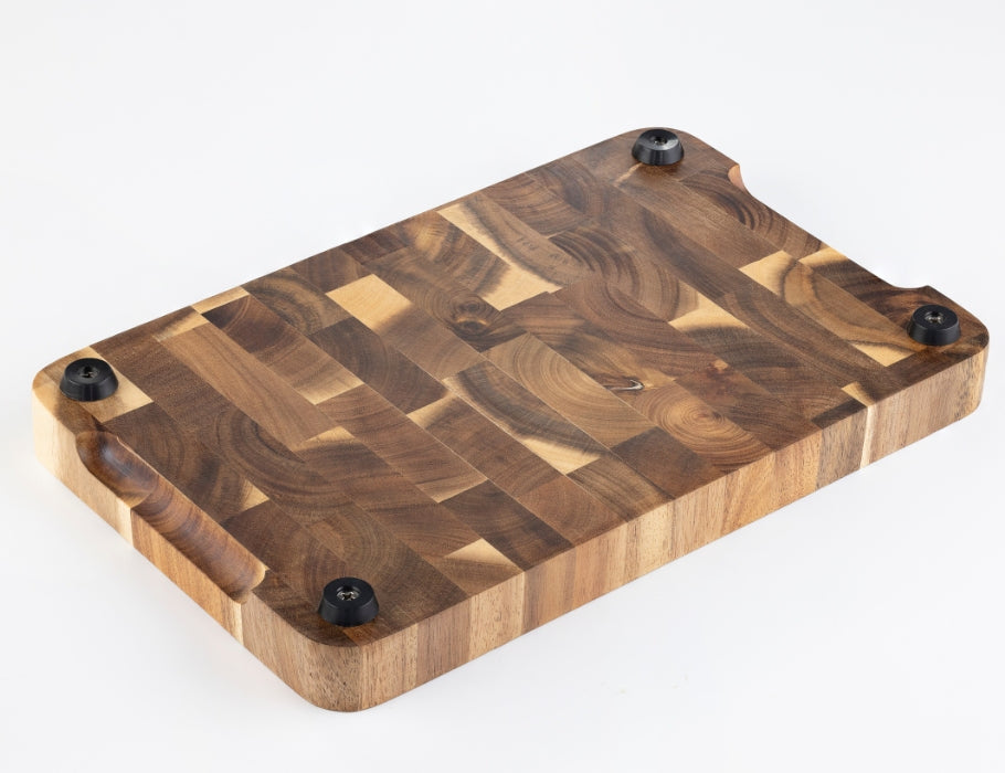 Onderkant van een Namture snijplank van acaciahout met vier zwarte antislip voetjes en afgeronde randen.