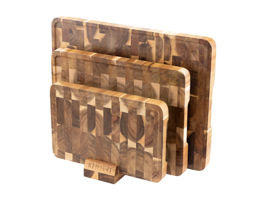 Drie Namture snijplanken van acaciahout in verschillende maten, rechtop geplaatst in de bijbehorende houten houder.