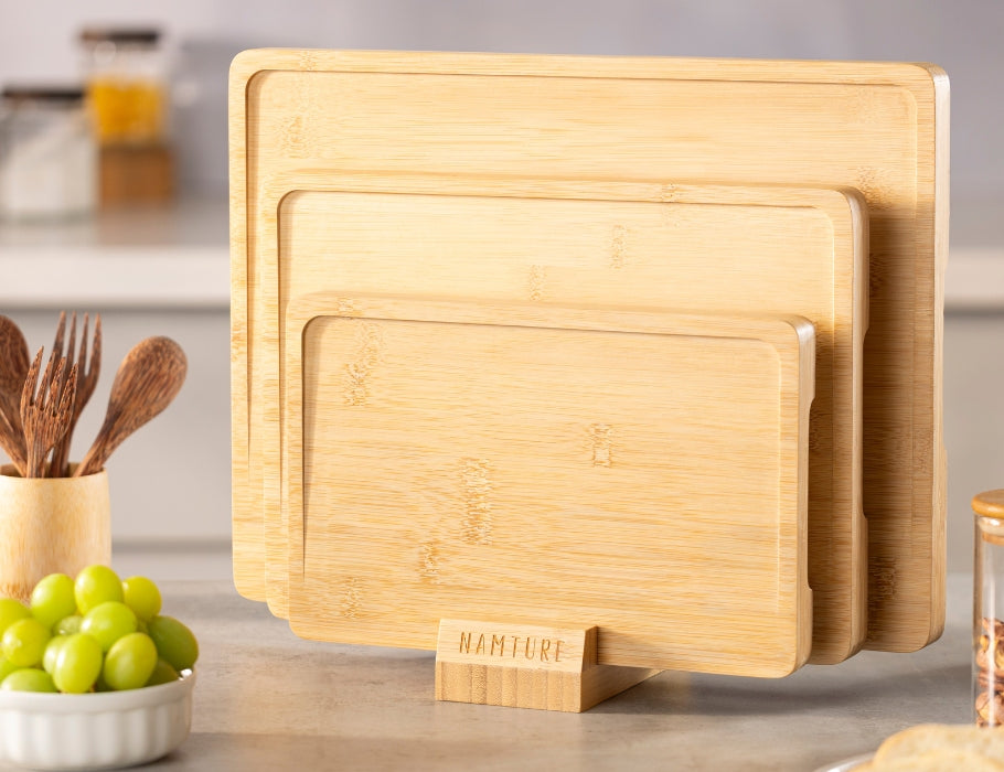 Set van drie Namture bamboe snijplanken in verschillende maten, staand in een houten houder op een keukenblad.